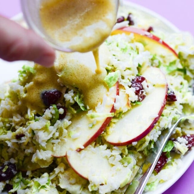 This Shaved Brussels Sprout Salad recipe is a chop it and toss it kind of dish, with sliced apples, dried cranberries, riced cauliflower, and shaved fresh Brussels sprouts. It's all tied together with the most creamy honey mustard dressing, and ready in under 15 minutes!