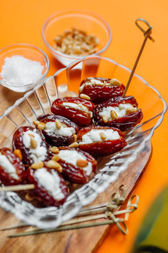 Goat cheese stuffed dates with pine nuts on an orange background