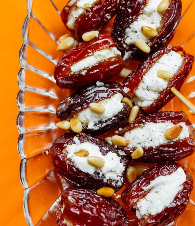 Goat cheese stuffed dates with pine nuts on an orange background