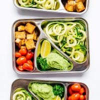Meal prep container with zucchini noodles on white background - This Zucchini Noodles Vegetarian Meal Prep is a low carb lunch solution that will have you looking forward to lunchtime! Packed with fresh veggies, avocado pesto, and crispy baked tofu.