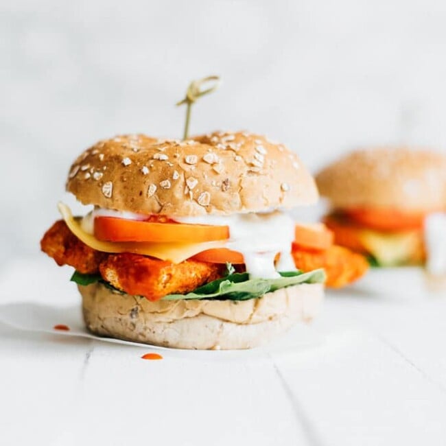 Vegetarian buffalo sandwich on white background - These Buffalo Tempeh Sandwiches are stuffed with crispy baked tempeh buffalo tenders, provolone cheese, and ranch dressing!