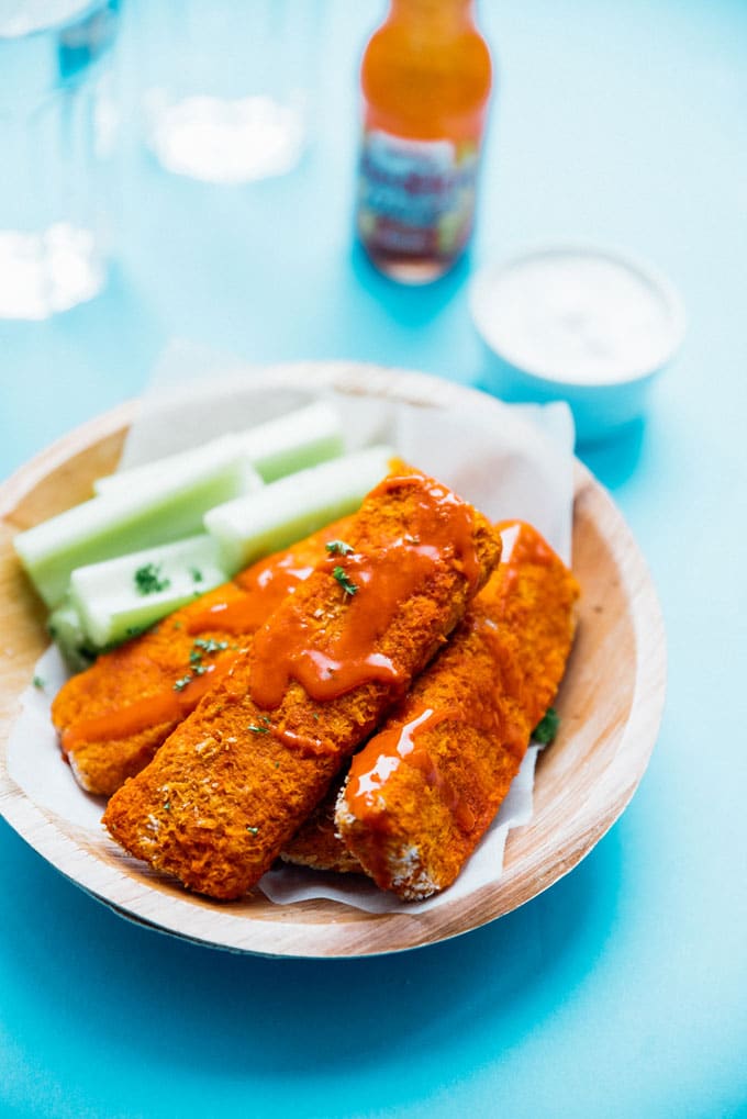 Tempeh tenders with buffalo sauce and celery on a blue background