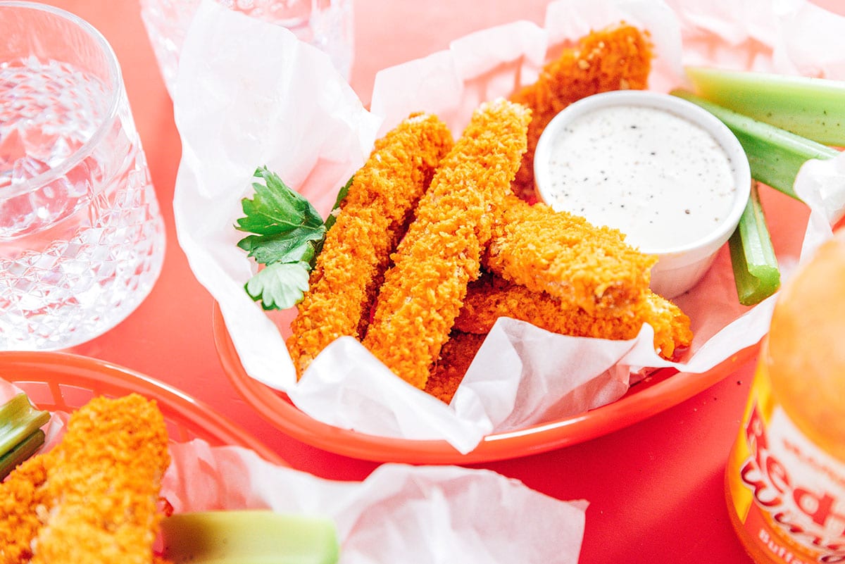 Tempeh tenders in a red basket with ranch dip and celery sticks