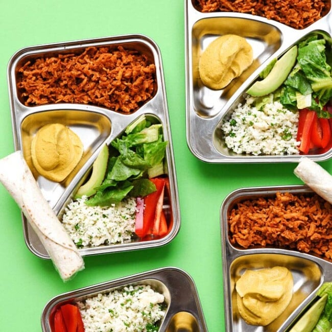 Meal prep boxes on a green background - This vegan Burrito Bowl Meal Prep is the perfect make ahead lunch that makes clean eating all week easy (and delicious)!