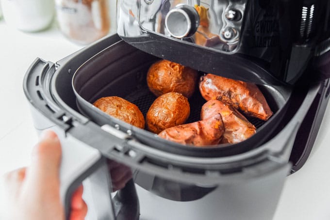 Potatoes in an air fryer with a white background