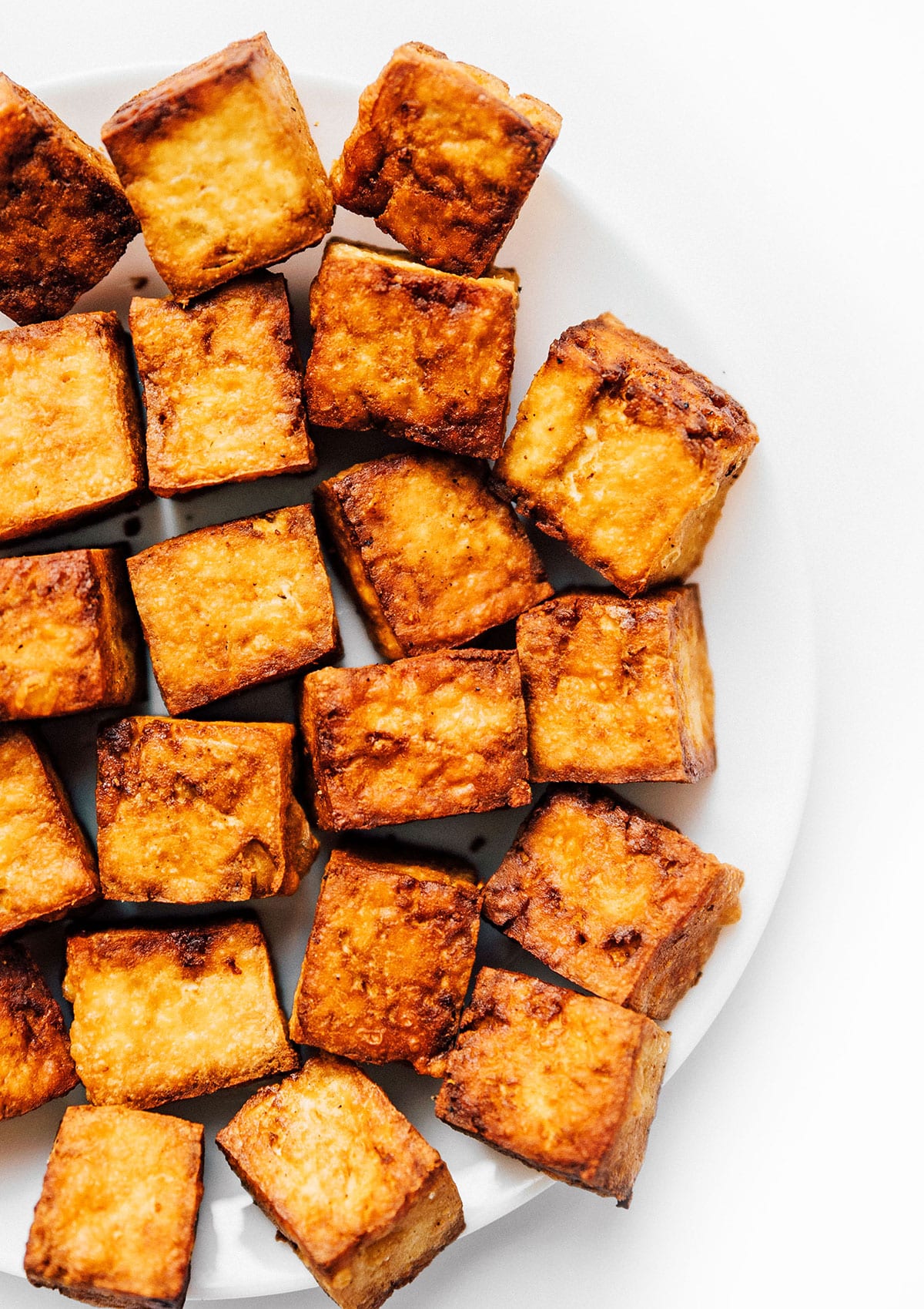 Blocks of crispy air fried tofu on a white plate.