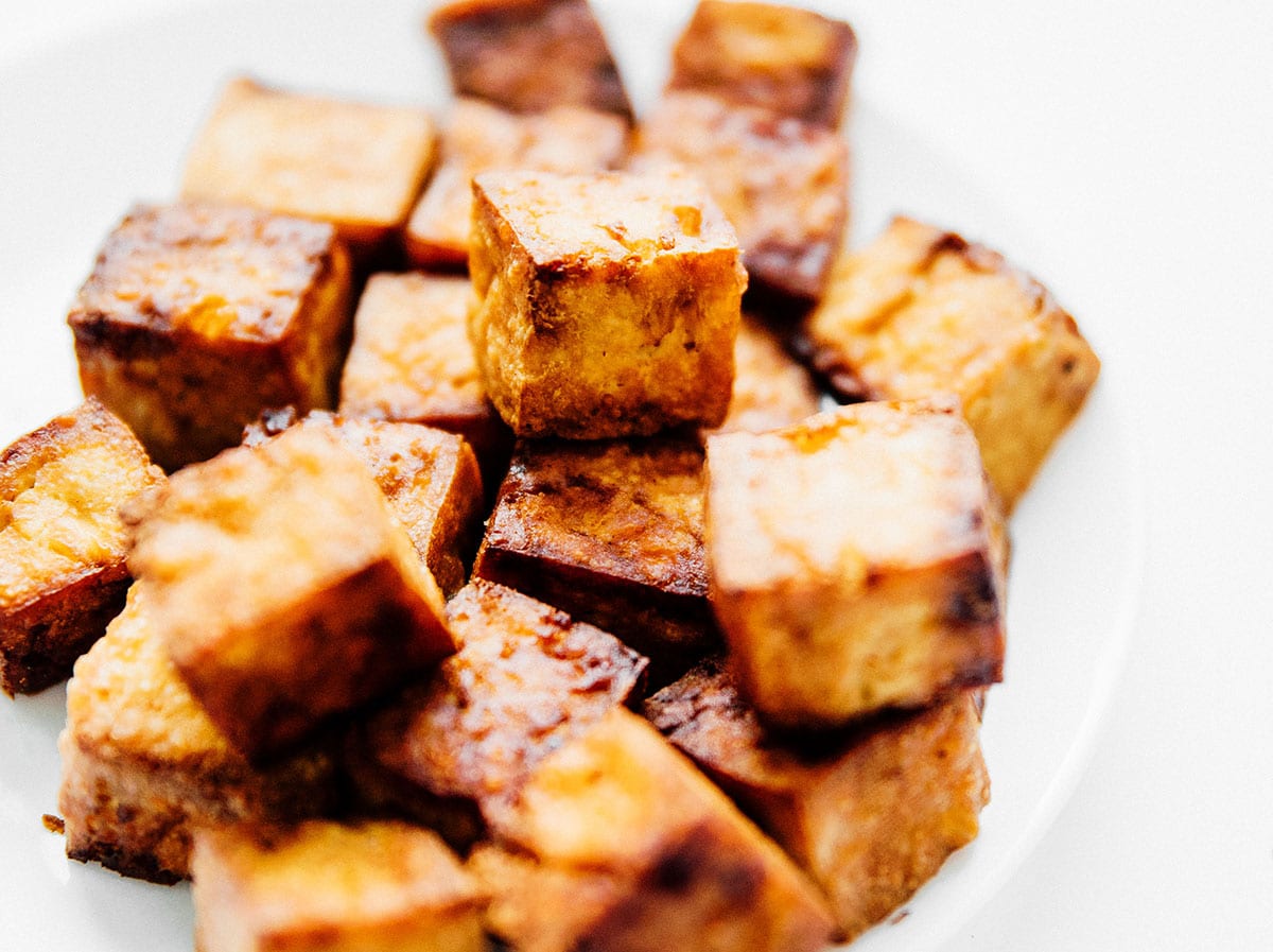 Blocks of crispy air fried tofu on a white plate.