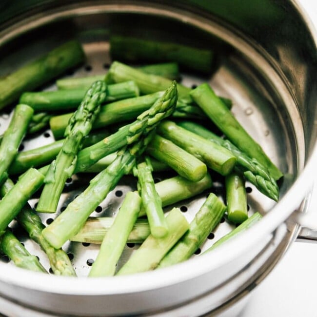 Asparagus in a steaming basket - The ultimate guide on how to cook asparagus! How to cook asparagus in the oven, in the microwave, or by blanching, steaming, or sautéing.