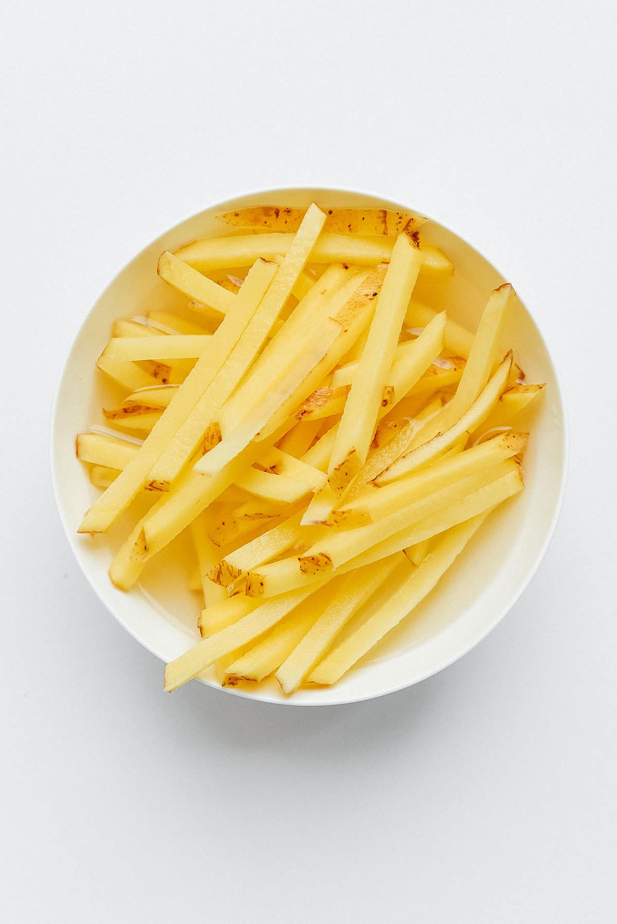 French fries soaking in a bowl of water.