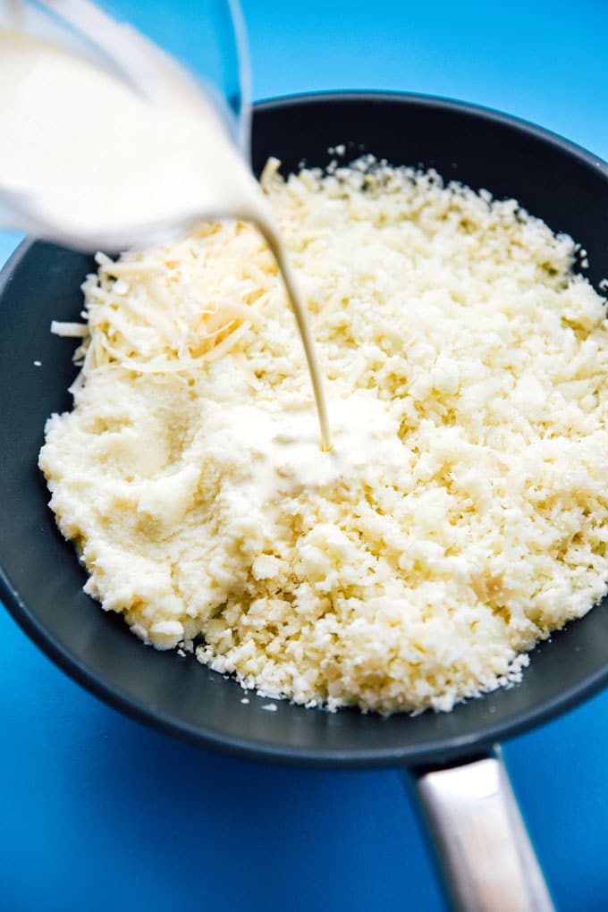 Cauliflower risotto recipe in a bowl on a blue background - This Cauliflower Risotto recipe is a low carb, keto-friendly twist on traditional risotto. Creamy and cheesy, without all the carbs!