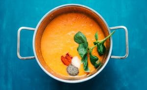 Fresh tomato soup in a pot with spices and basil