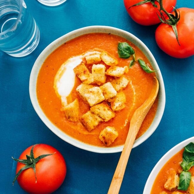 Fresh tomato soup in a bowl with homemade croutons and roma tomatoes
