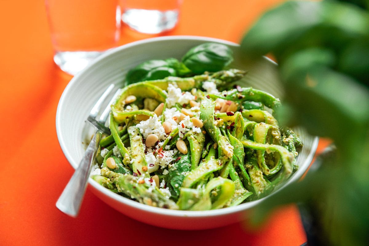 Asparagus noodles in a bowl with pesto and feta cheese.
