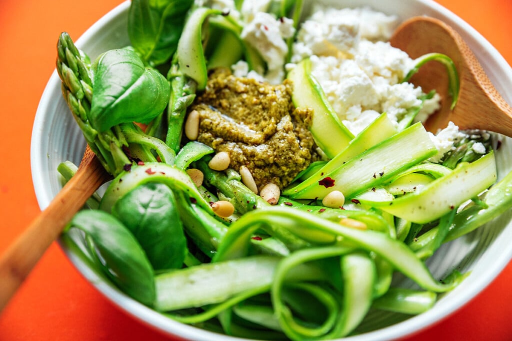 Asparagus noodles in a bowl with pesto and feta cheese.