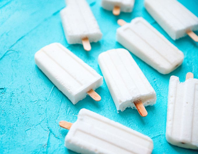 Marshmallow Coconut Popsicles recipe with white homemade popsicles on a blue background.