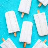 Marshmallow Coconut Popsicles recipe with white homemade popsicles on a blue background.
