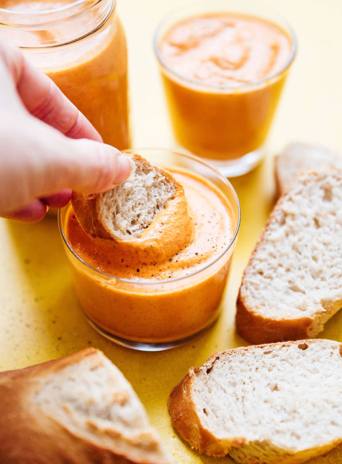 Romesco sauce recipe in a jar with a piece of bread.