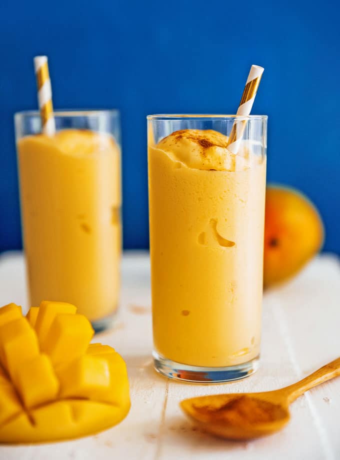 Mango lassi in a glass with a straw