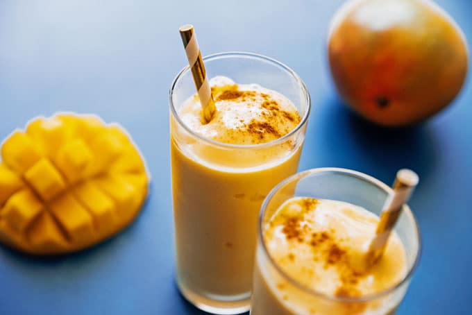 Mango lassi in a glass with a straw