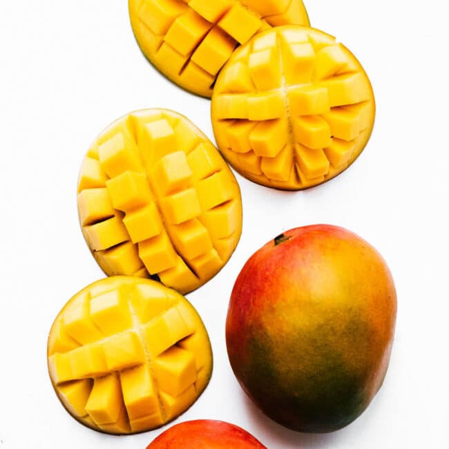 Cut mangoes on a white background.