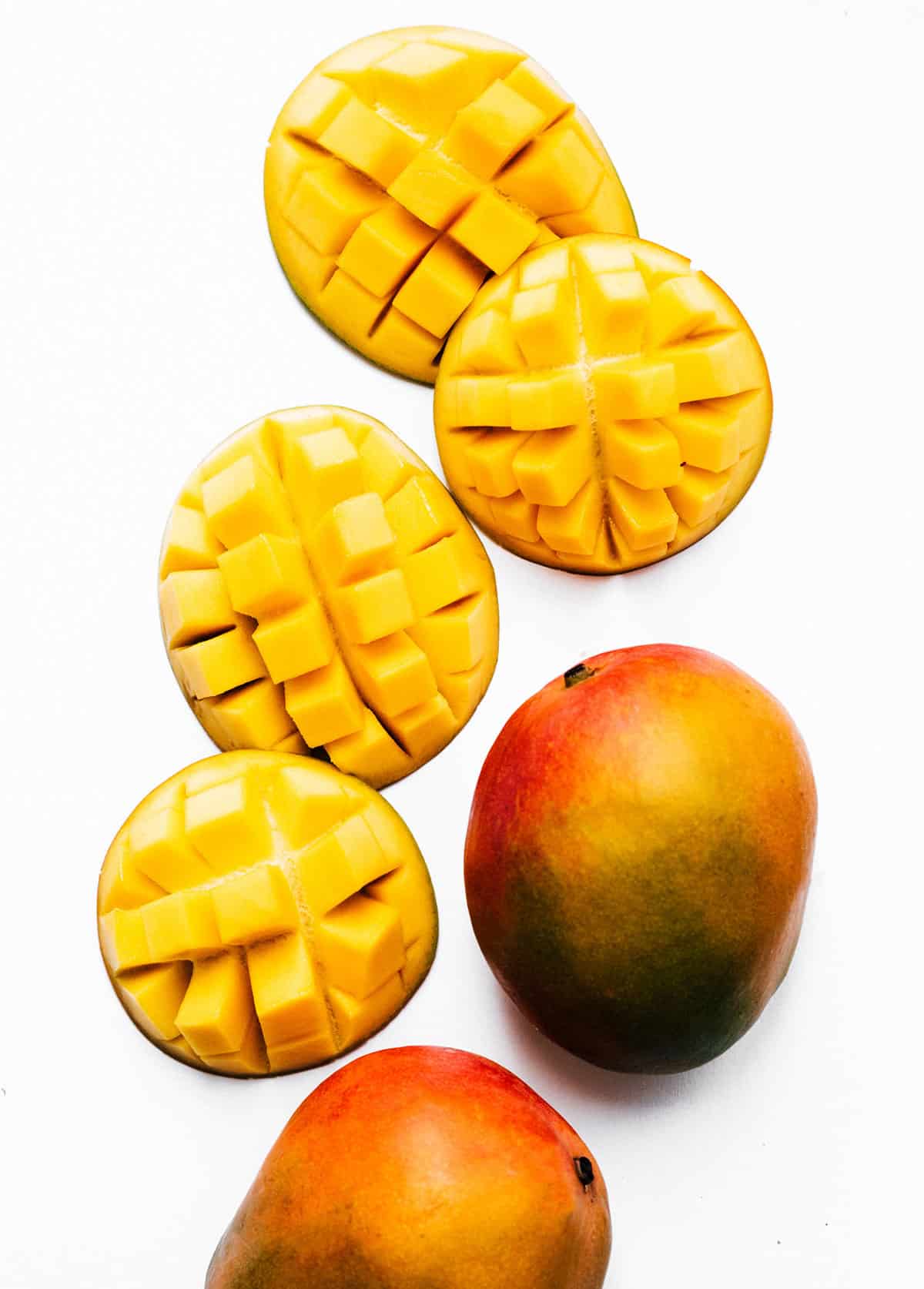 Cut mangoes on a white background.