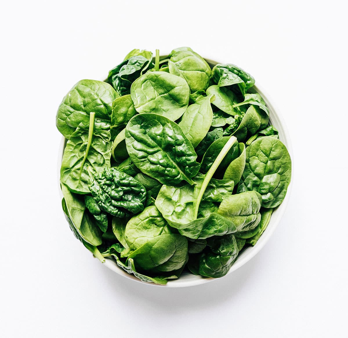 Spinach leaves in a bowl on a white background