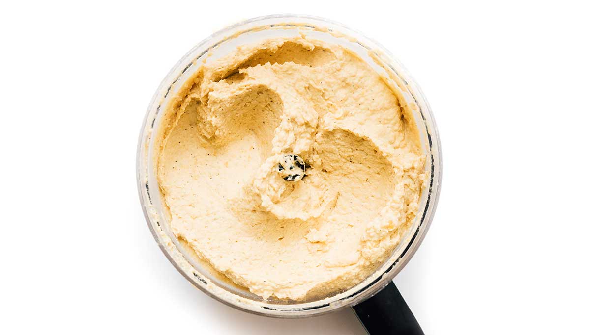 Hummus in a food processor on a white background