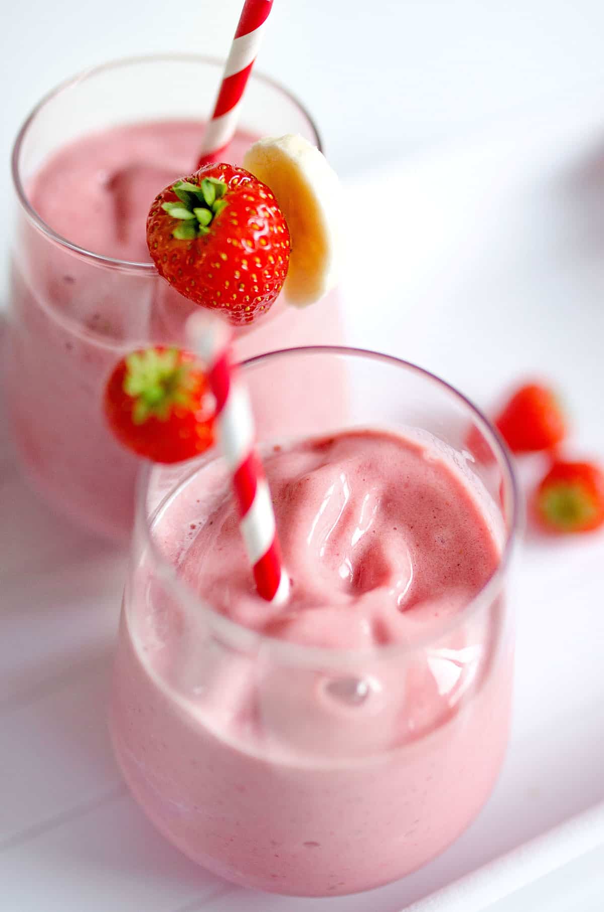 Strawberry banana smoothie with a straw in a glass from above.