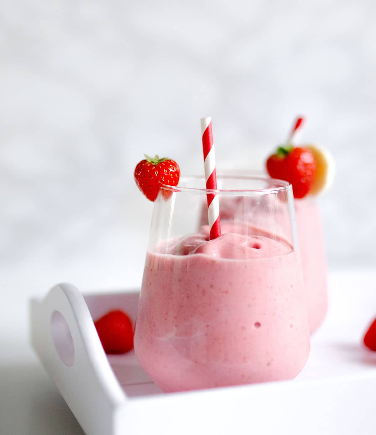 Strawberry banana smoothie with a straw in a glass.