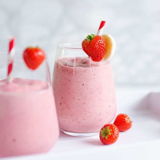 Strawberry banana smoothie with a straw in a glass.