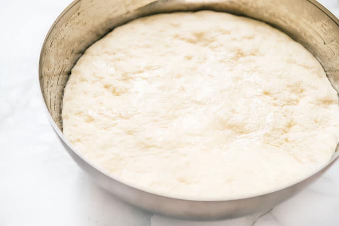 Kneaded pizza dough after rise on a marble background