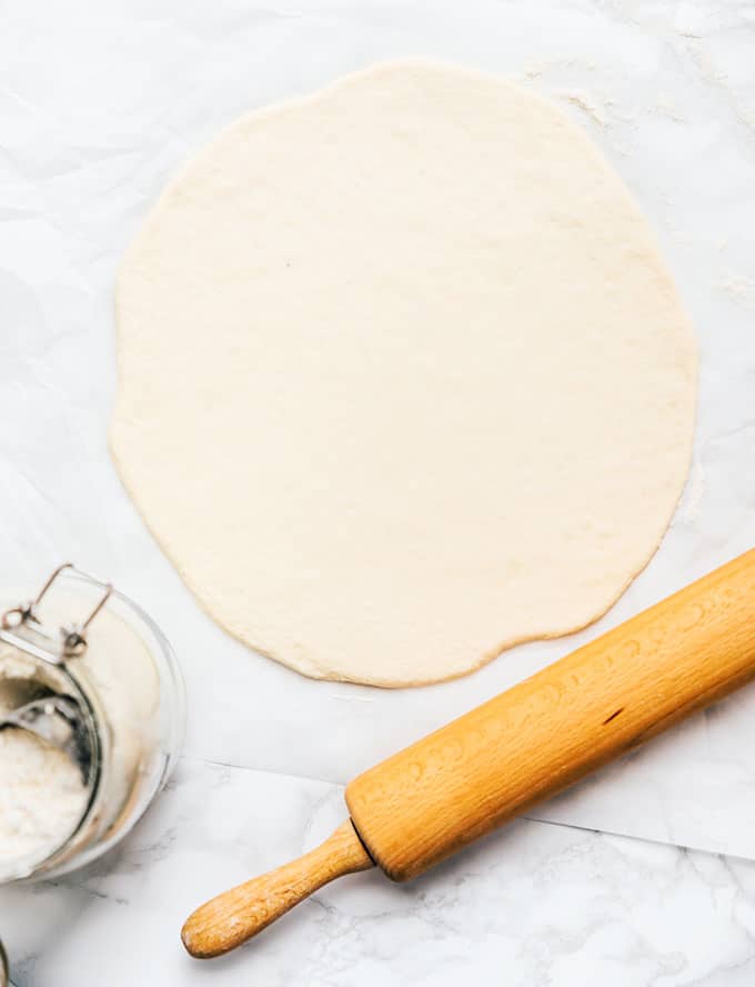 Rolled out pizza dough on a marble background