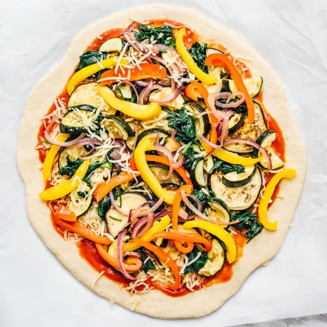 Homemade pizza dough on a marble background with toppings
