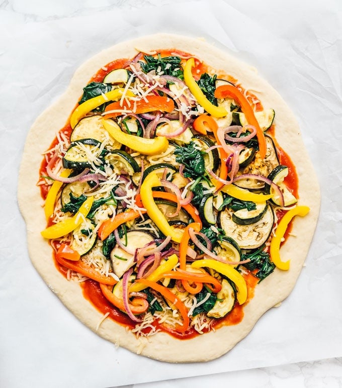 Homemade pizza dough on a marble background with toppings