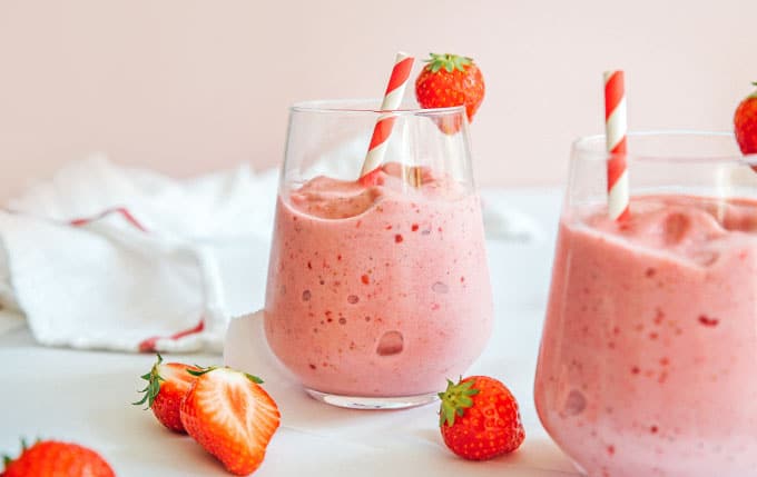 Strawberry smoothie in a glass with a striped straw