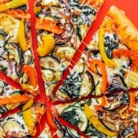 Veggie pizza slices on red background