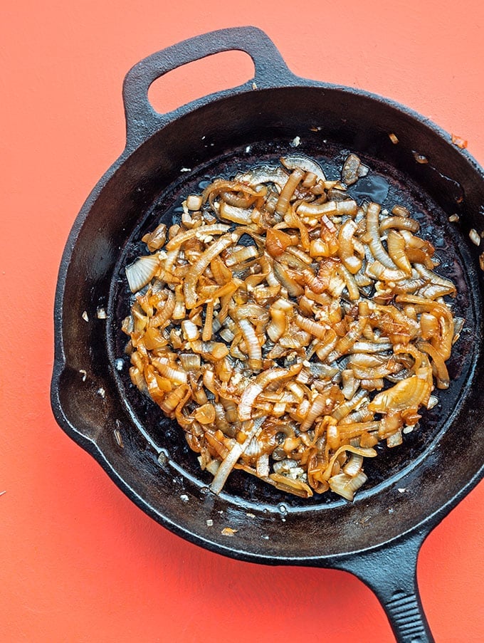 Caramelized onions in a cast iron skillet on pink background