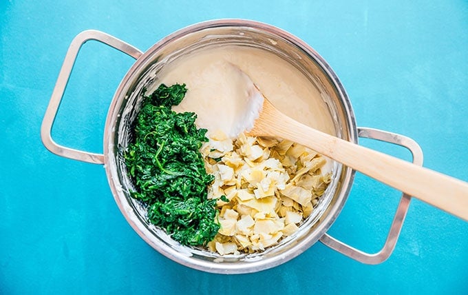Ingredients to make greek yogurt spinach artichoke dip in a stove pan