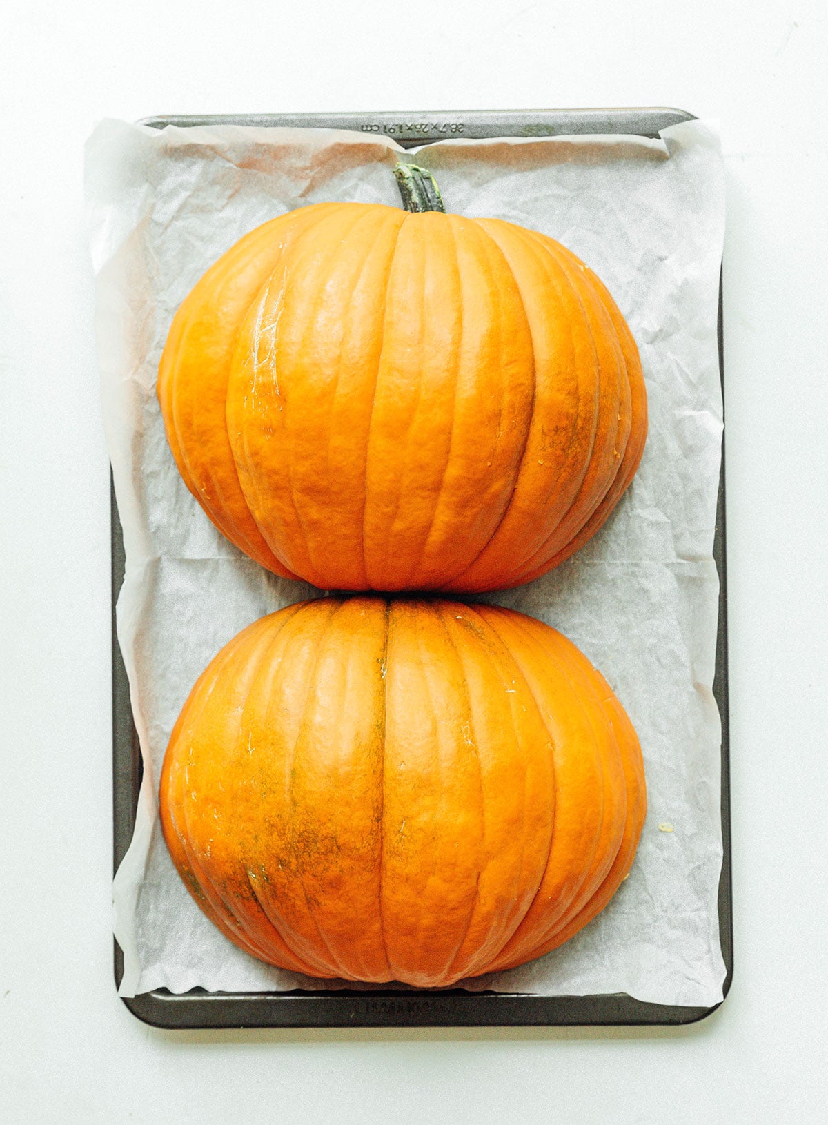 Two pumpkin halves on a baking sheet