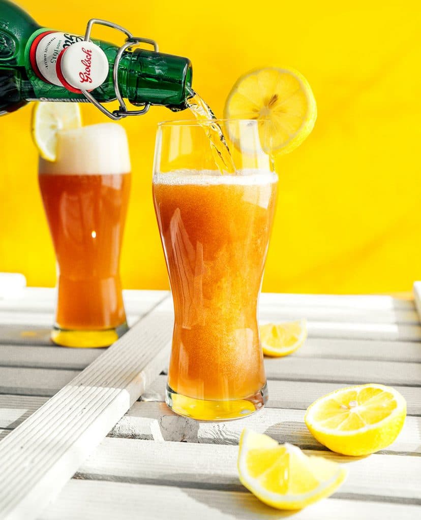 Pouring Grolsch beer into a glass with a yellow background