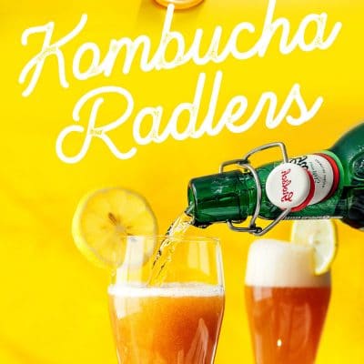 Kombucha radler in a glass with a lemon on a yellow background