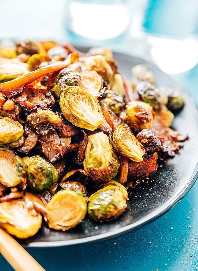Oven roasted Brussels sprouts with vegan bacon on a black plate