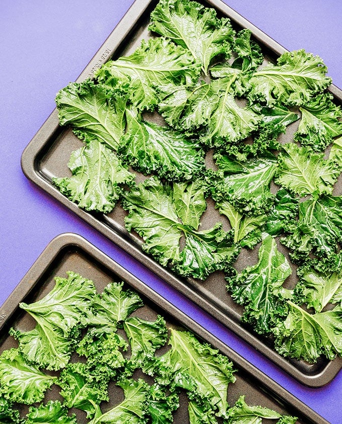 Baking sheet of kale chips on a purple background
