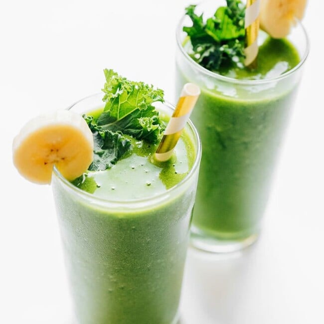 Green kale smoothie in a glass with paper straw