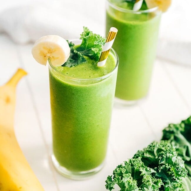 Kale green smoothie in a glass with paper straw