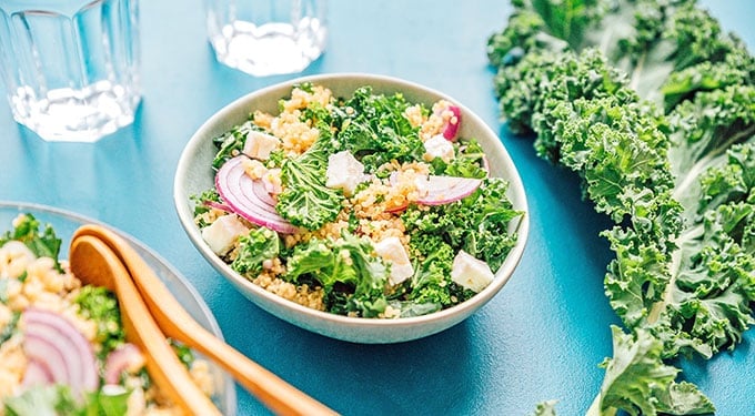 Quinoa kale salad in a bowl on a blue background