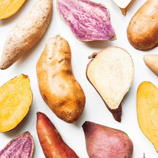 Many colors of sweet potatoes on a white background.