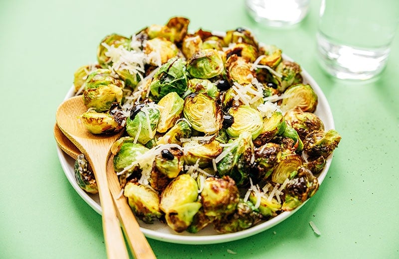 Air fried brussels sprouts in a bowl with green background