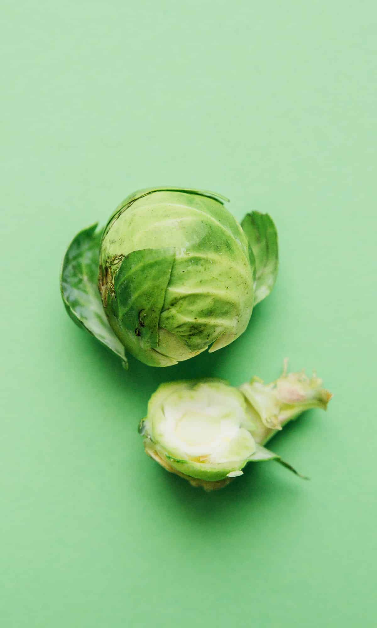 Cutting Brussels sprouts on a green background.