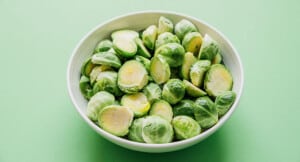Brussels sprouts in a bowl on a green background.